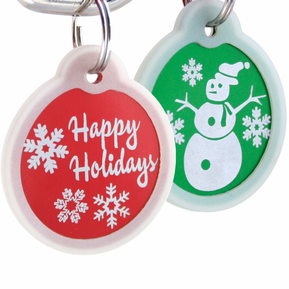 Front view of two Christmas dog ID tags: red tag reading Happy Holidays and green snowman tag with glow-in-the-dark silencers on white background