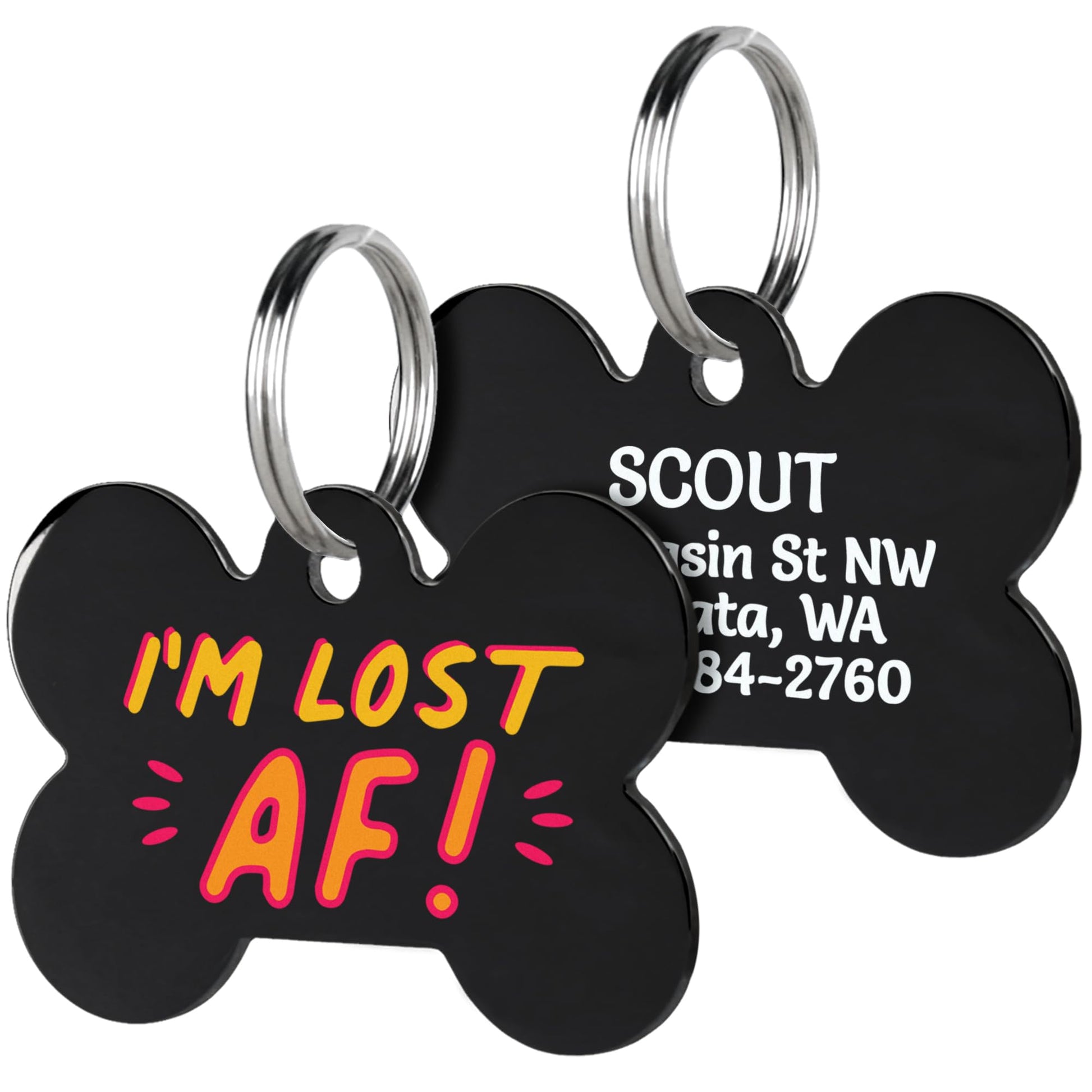 Close-up of black acrylic dog ID tags showing colorful IM LOST AF front text, engraved contact info on back, and metal split rings on white background