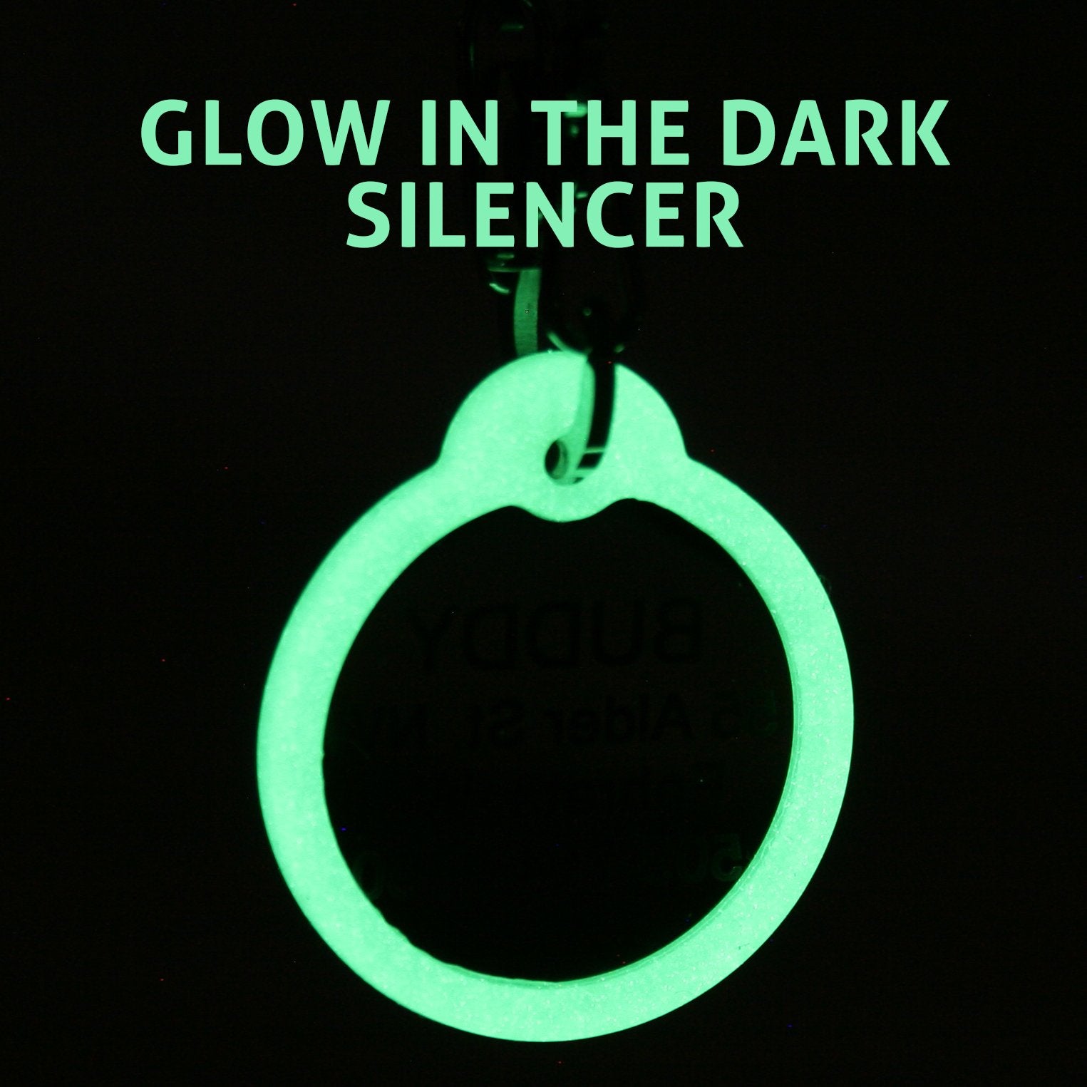 Close-up of dog ID tag silencer glowing green against black background with overlaid text GLOW IN THE DARK SILENCER