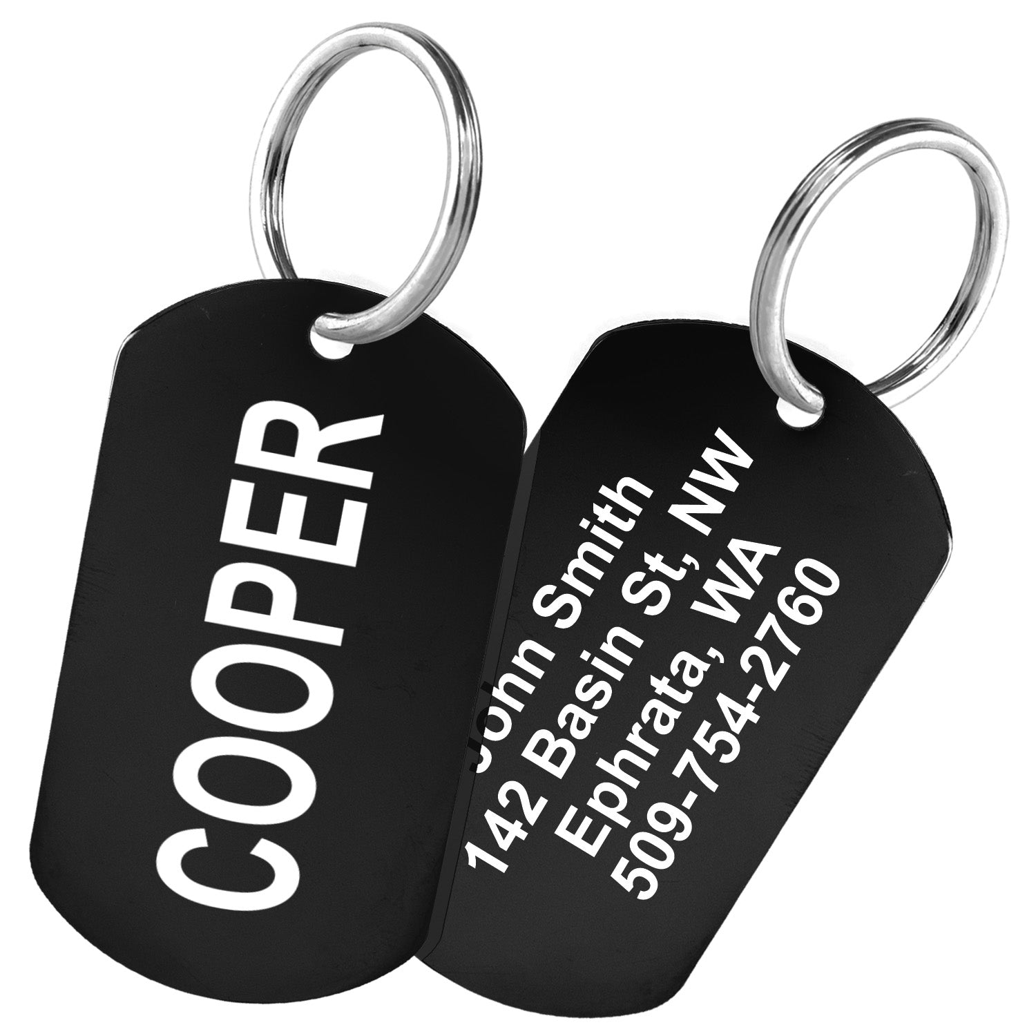 Angled view of two black stainless steel rectangle pet ID tags with split key rings showing white laser engraving with sample name COOPER and sample address on white background