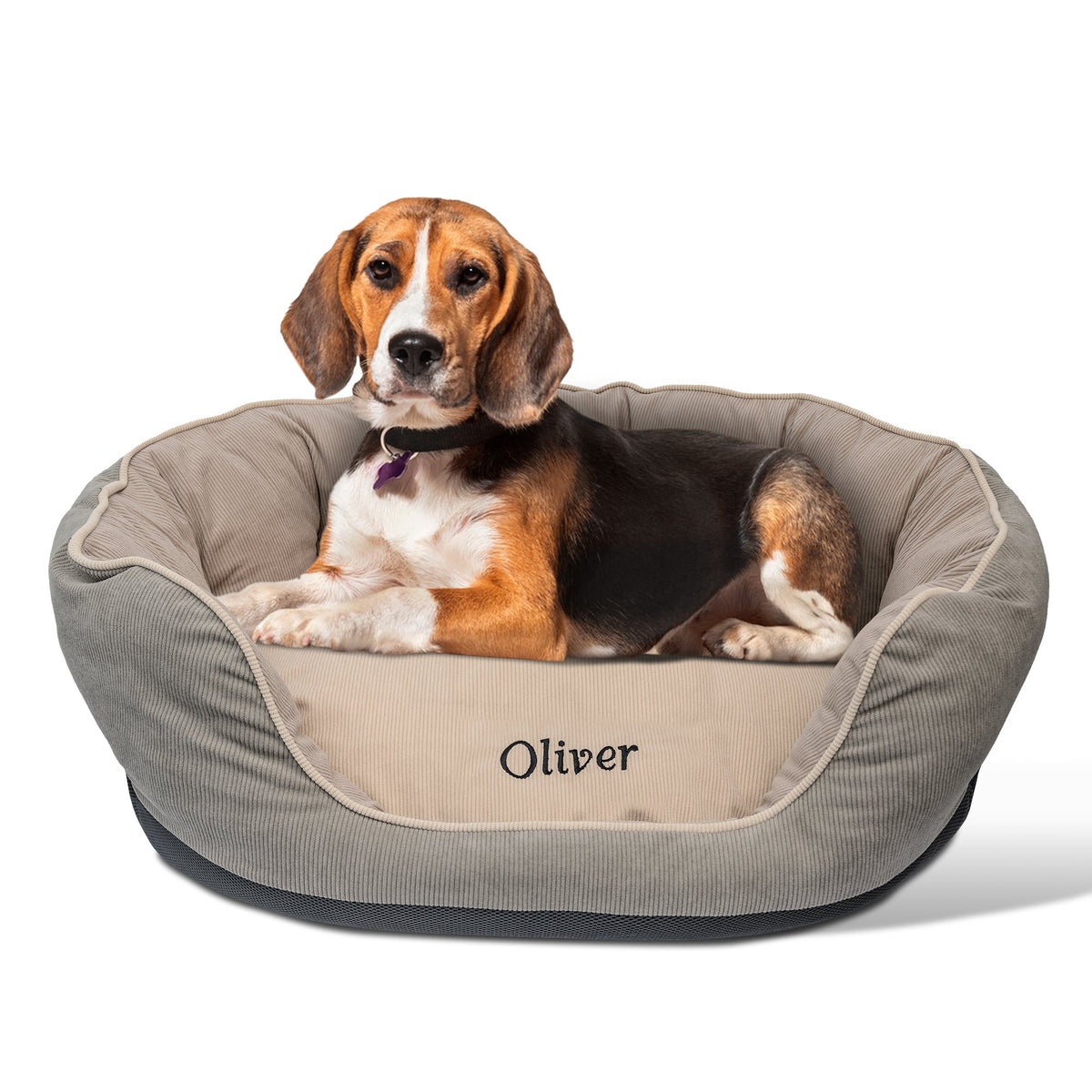 Angled front view of round beige embroidered waterproof dog bed showing embroidered name Oliver and supportive rails