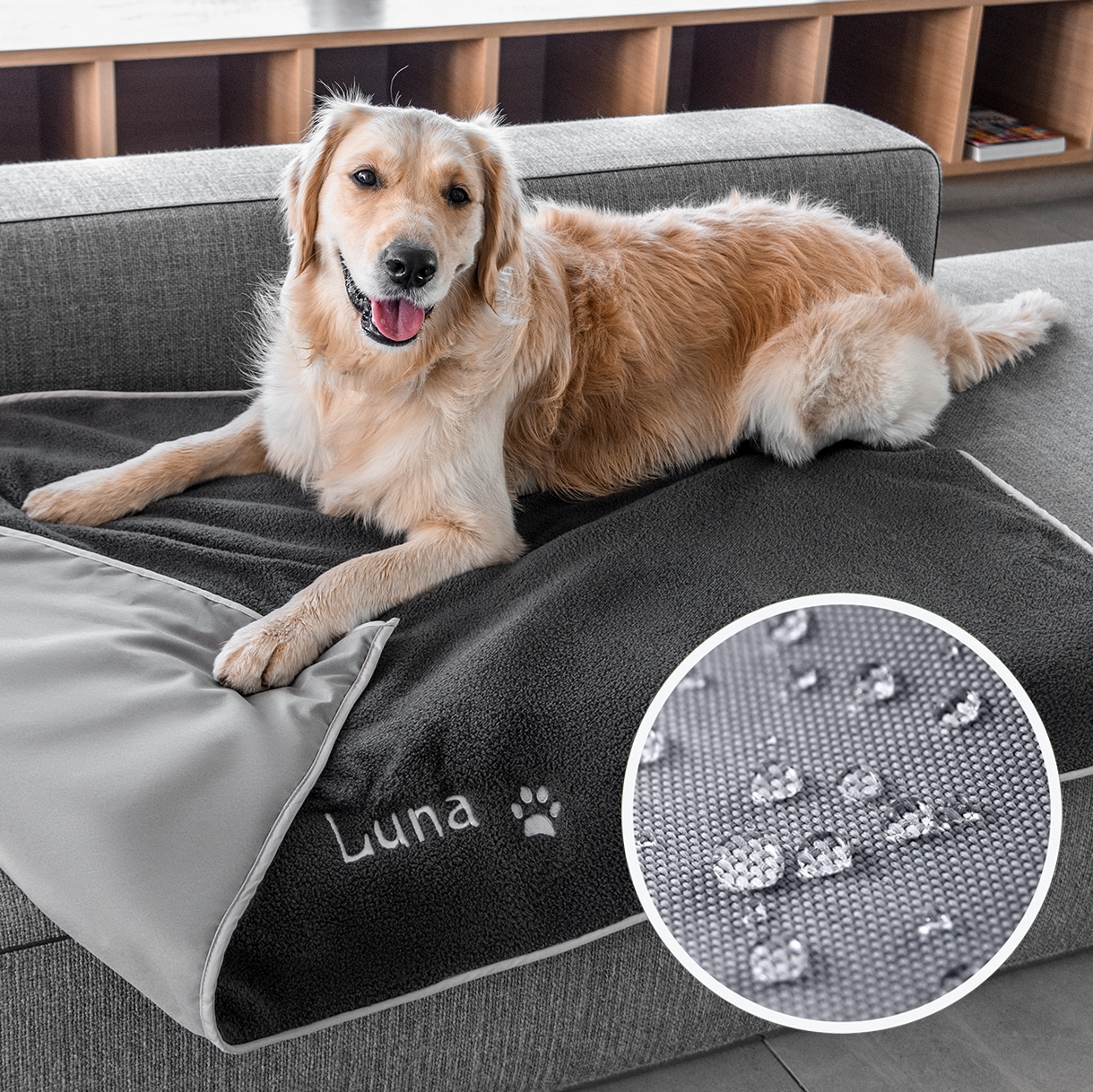 Angled view of personalized gray fleece dog blanket embroidered Luna with paw print, showing water-resistant backing on couch