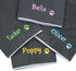 Stacked personalized fleece dog blankets showing embroidered names and paw-print accents in assorted thread colors on gray fleece
