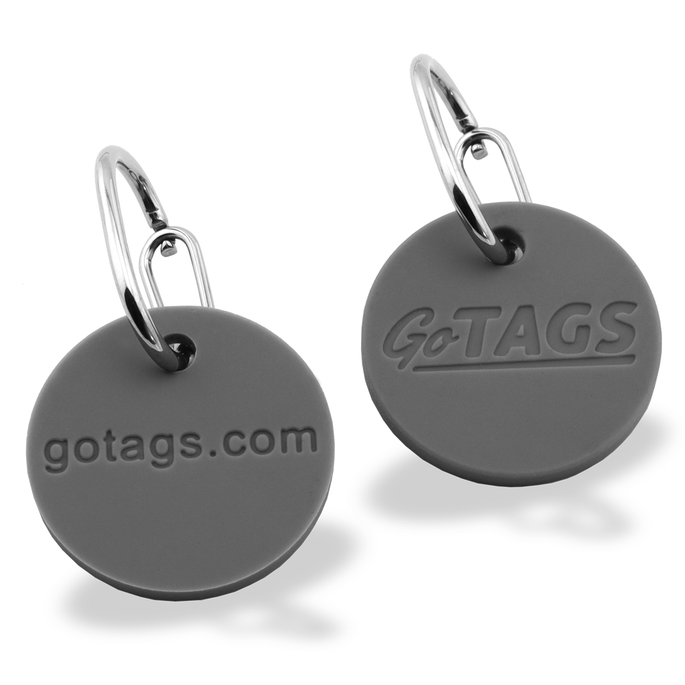 Front view of two gray round tag silencers with embossed GoTAGS and gotags.com attached to metal quick clips on white