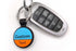 Front view of blue-orange AirTag keychain with two-line engraved Custom Text, metal split ring and attached car key on white